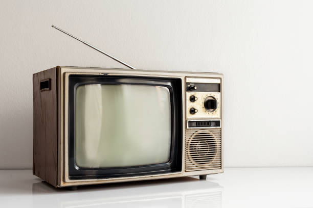 istock Vintage old television on white table with antenna in front of white wall background. 1461069371