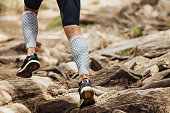legs runner in compression calf sleeve running over stones