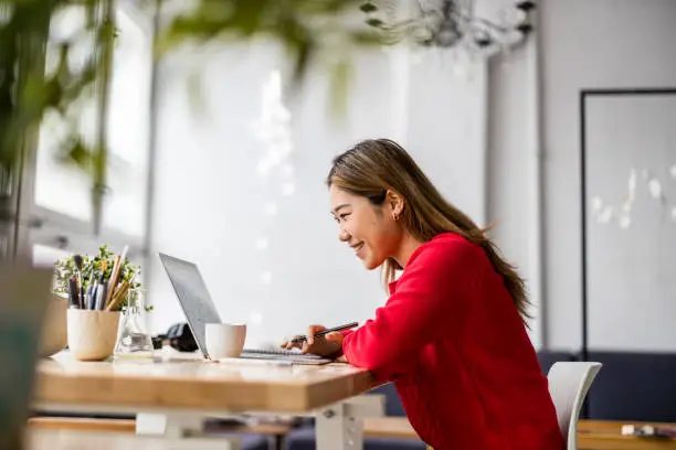 Young woman sitting at desk working on laptop