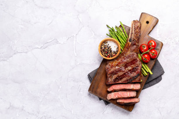 Medium rare grilled Tomahawk beef steak with asparagus Medium rare grilled Tomahawk beef steak with asparagus. Flat lay with copy space steak stock pictures, royalty-free photos & images