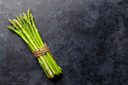 Bunch of fresh asparagus on stone table. Flat lay with copy space
