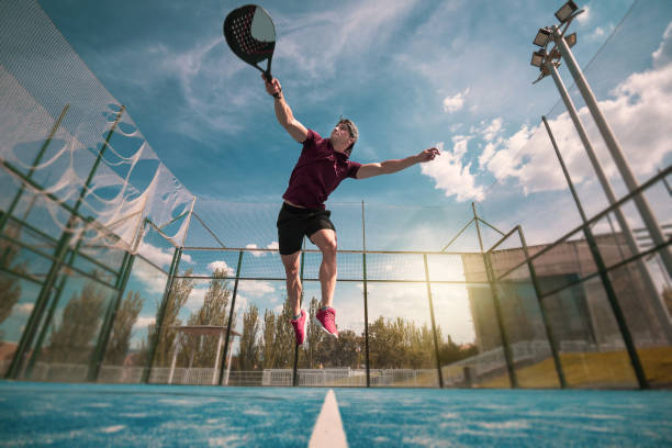 a young padel player jumps to hit the ball in an outdoor game. - the paddle racket imagens e fotografias de stock