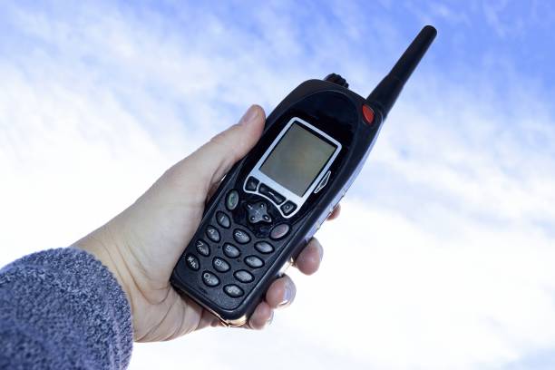 Using a walkie talkie, telecommunications equipment against blue sky