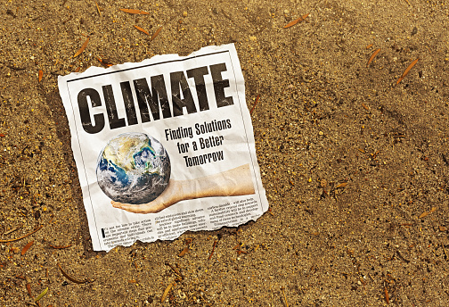 Newspaper clipping about solutions to the climate crisis lies in arid sand in bright sunlight, an image full of irony. Text was written from scratch by the photographer, who also did the design, so this image is free of third-party copyright and may be used without restriction. Public domain satellite Earth image from https://www.nasa.gov/multimedia/imagegallery/image_feature_2159.html