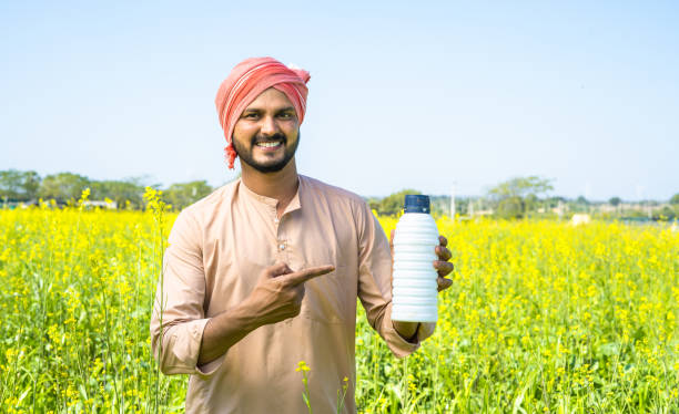 istock Confident young farmer showing fertilizer bottle by pointing finger while looking at camera at farmland - concept of product recommendation, agricultural and promotion. 1461084468