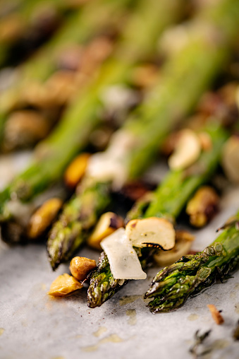 Close up of  asparagus stalks made with pistachios, capers, parmesan cheese, garlic and thyme. Colour, vertical format with some copy space.