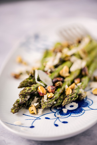 Fresh asparagus made with pistachios, capers, parmesan cheese, garlic and thyme. Colour, vertical format with some copy space.