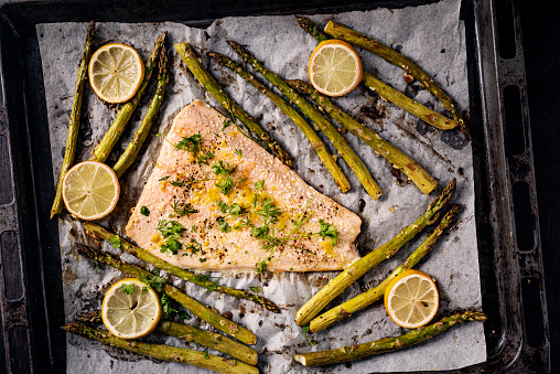 Baked salmon with asparagus. You will need, salmon, fresh asparagus, lemon juice, dill, olive oil, garlic, seasoning and yoghurt. Colour, horizontal with some copy space. Bake 108C/375/F  for around 15 minutes.