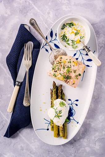 Baked salmon with asparagus with a yoghurt based dill and lemon flavoured dressing. You will need, salmon, fresh asparagus, lemon juice, dill, olive oil, garlic, seasoning and yoghurt. Colour, vertical with some copy space. Bake 108C/375/F  for around 15 minutes.
