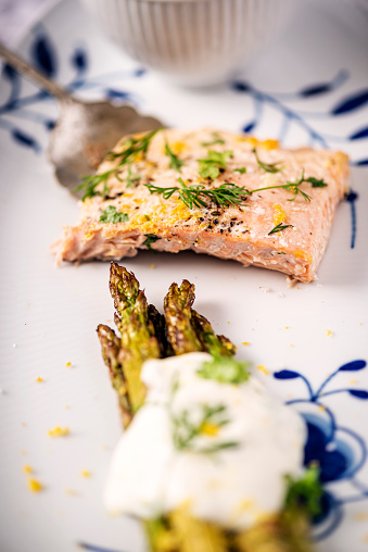 Baked salmon with asparagus with a yoghurt based dill and lemon flavoured dressing. You will need, salmon, fresh asparagus, lemon juice, dill, olive oil, garlic, seasoning and yoghurt. Colour, vertical with some copy space. Bake 108C/375/F  for around 15 minutes.