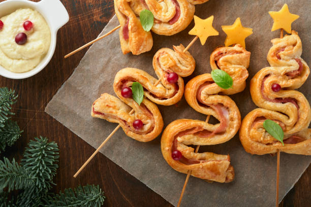 istock Christmas or New Year appetizer. Christmas tree shape puff pastry buns with cheese and ham. Group of Christmas tree shapes on wooden board. Festive idea for Christmas or New Year dinner. Top view. 1461092248