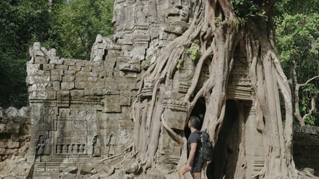 Male Tourist Gazing at The Khmer temple of Ta Som - Tree growing atop the historical main gateway