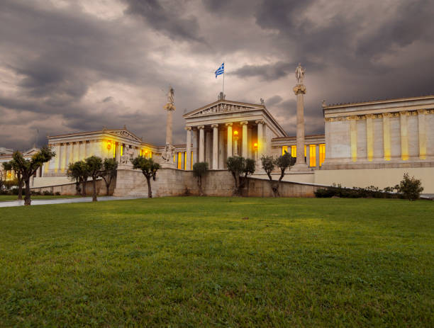 academia de atenas una columna de mármol con esculturas de apolo y atenea, sócrates y platón en atenas, grecia por la noche - sócrates filósofo griego fotografías e imágenes de stock