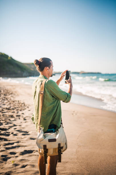 Young traveler enjoying his summer vacation and using his smart phone