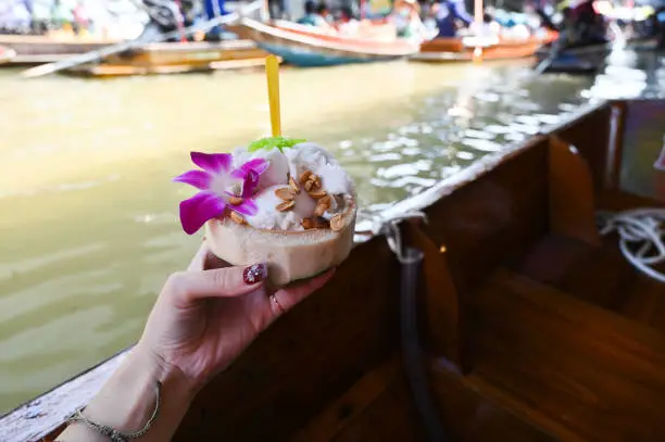 Photo of Hand holding coconut ice cream in Floating Market Dumnoen Saduak