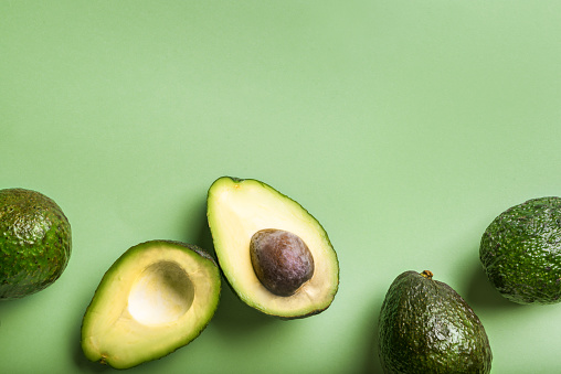 Haas avocados on green background, top view, copy space. Healthy fresh organic avocado closeup.