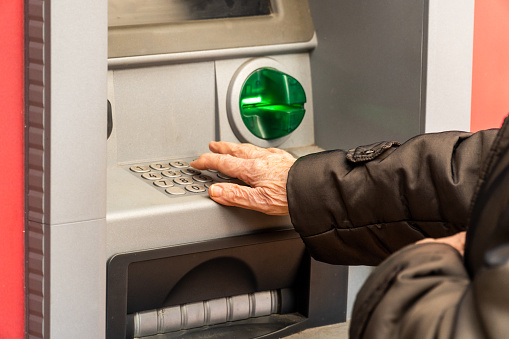 senior woman hands typing the pin code in the ATM