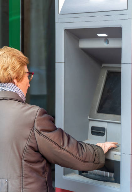 istock Elderly woman using the ATM bank 1461104138