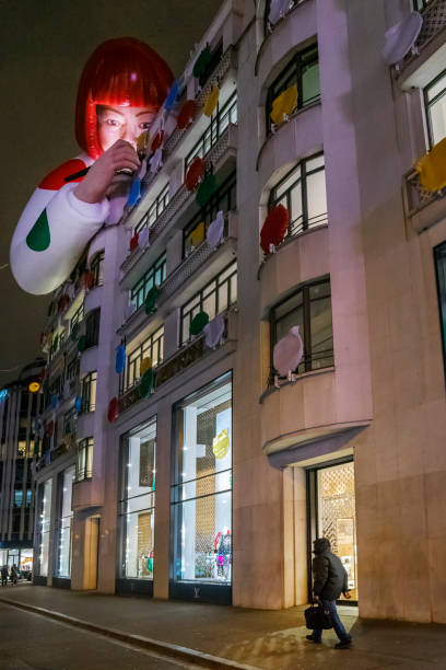Paris, France — January 28, 2023: A man walks outside a Louis Vuitton outlet with a large sculpture of Japanese artist Yayoi Kusama and coloured dots installed on the facade.