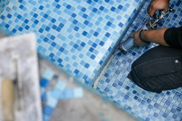 Unrecognizable male Caucasian worker lying down ceramic tiles in a room.
