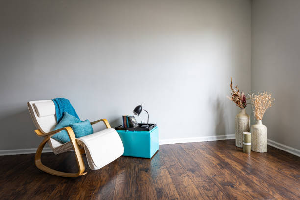 Corner of an empty room with only rocking armchair and dry plants arrangement in clay vases.