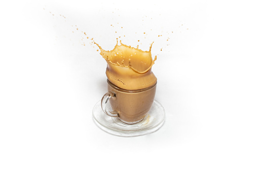 Crown splash on a transparent glass coffee cup with milk, isolated on white background