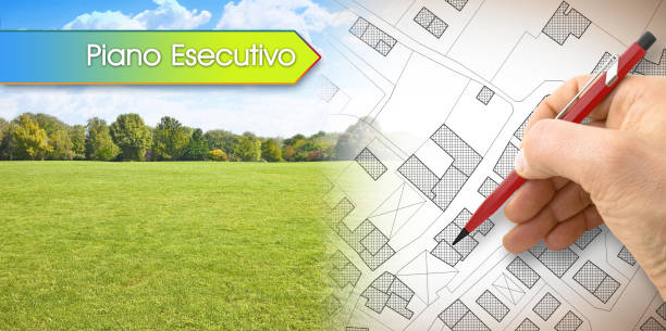 istock Executive urban plan, in Italian language Piano Esecutivo, concept with architect drawing an imaginary cadastral map of territory with buildings, fields and roads against a green area 1461111763