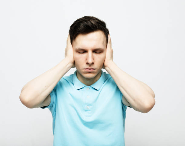 istock young man covers his ears with his palm over grey background 1461114060