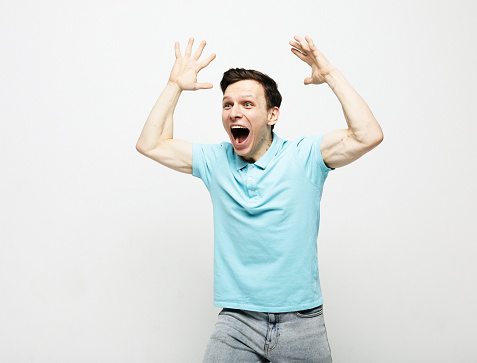young man wearing blue t-shirt celebrating victory over grey background