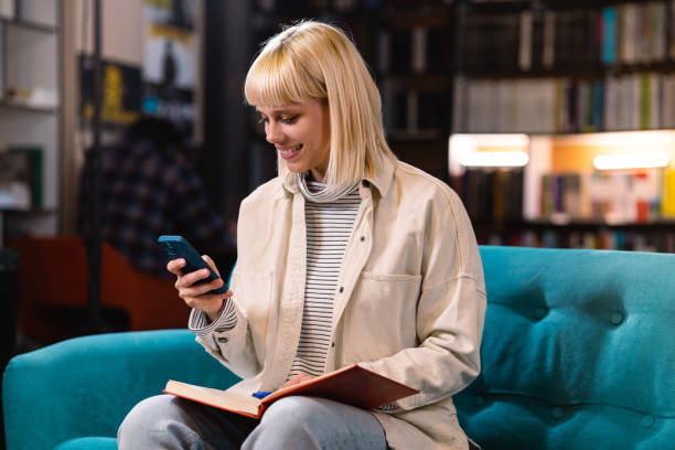 istock Young woman using smart phone in the library 1461116184