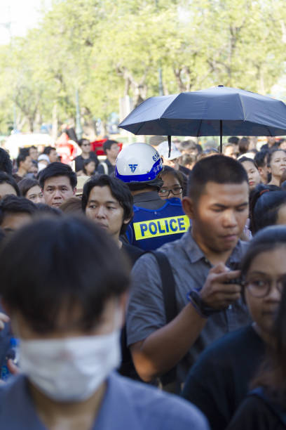 el policía tailandés está parado entre la multitud y las colas de los tailandeses - phumiphon aduldet fotografías e imágenes de stock