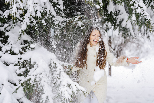Playful young woman having fun in snow
