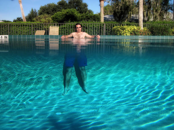 Partially underwater shot of man standing in outdoor swimming pool with clear clean water in Florida
