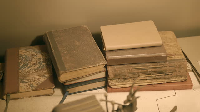 A table with a stack of old books of different colors and thicknesses
