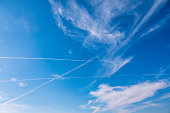 Blue sky with airplane trails and clouds.