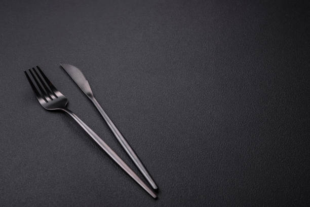 istock Metal kitchen knife and fork on a dark textured concrete background 1461132115
