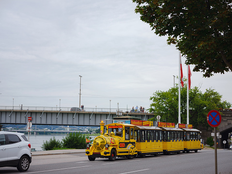 Linz, Austria - August 6, 2022 : The red yellow tourist train stands in the middle of the street in the center of the city of summer day.