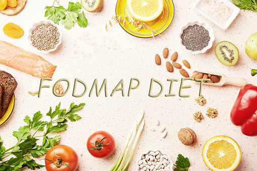 FODMAP diet with text in center. Mediterranean healthy low ingredients - vegetables, greenery, fruits, nuts, beans, egg, flax seeds, chia seeds. Flat lay.