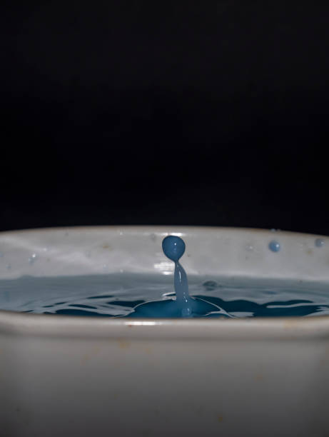 istock Color fresh blue milk drops into white milk in cup with black background 1461138779