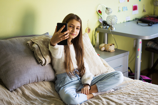 Portrait of  teenage girl looking at front mobile phone camera