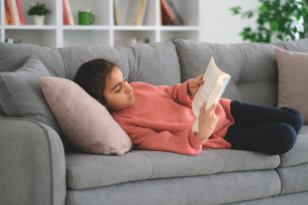 istock Little girl reading the book on sofa 1461144229