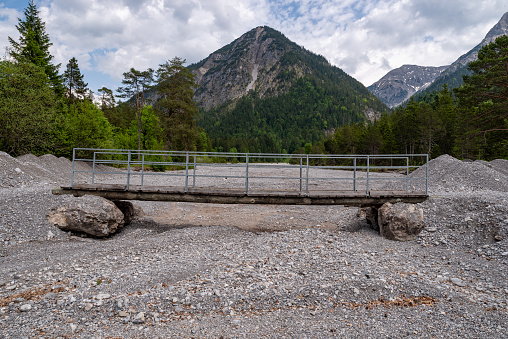 Temporary bridge in the middle of the rubble, seemingly in the nothing, mountain peaks in the background, Austria