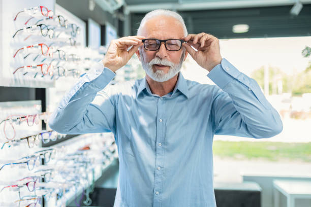 istock Senior man looking at different eyeglasses to buy looking at camera 1461145713