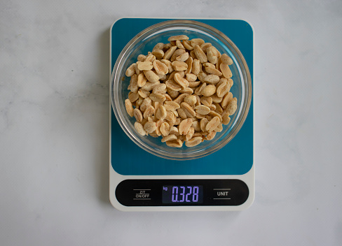 Electronic kitchen scales, peanuts on a light background
