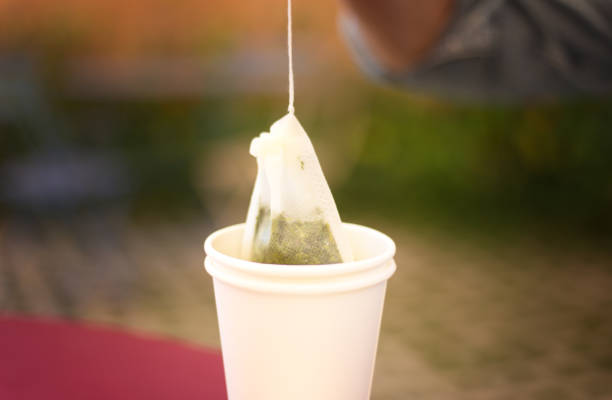 Hand Removing Tea Bag from Paper Cup