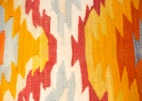 A close-up detail of a vintage wool Turkish kilim rug in orange, yellow and white.