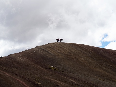 Group of people hiking on hill ridge Cordillera de Arcoiris colorful Palccoyo rainbow mountain Palcoyo Cuzco Peru in South America
