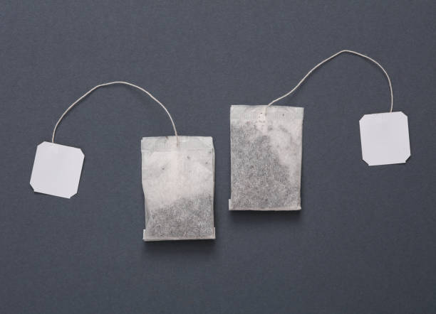 istock Two tea bags with blank white labels on a dark gray background. Top view 1461156732