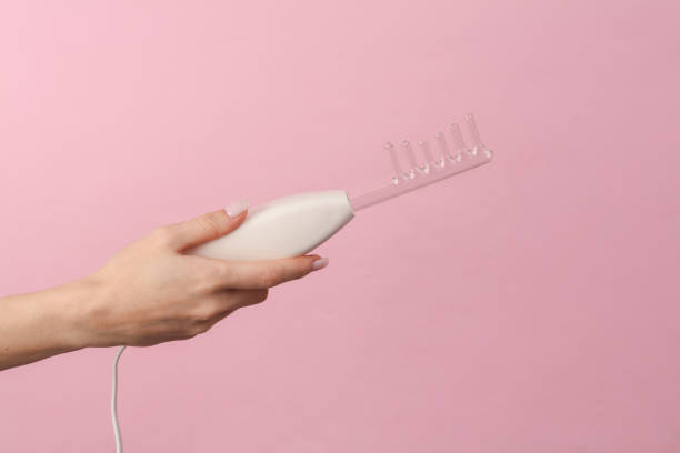 istock A woman's hand holds a device for local dorsenvalization on a pink background. Treatment of acne, skin diseases and alopecia 1461158156