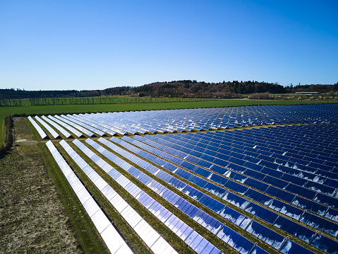 Aerial view of sunlight falling on voltaic solar panels over agricultural landscape against clear sky at solar power station